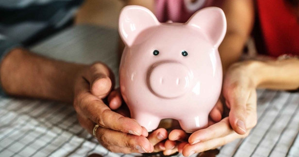 person holding pink piggy coin bank