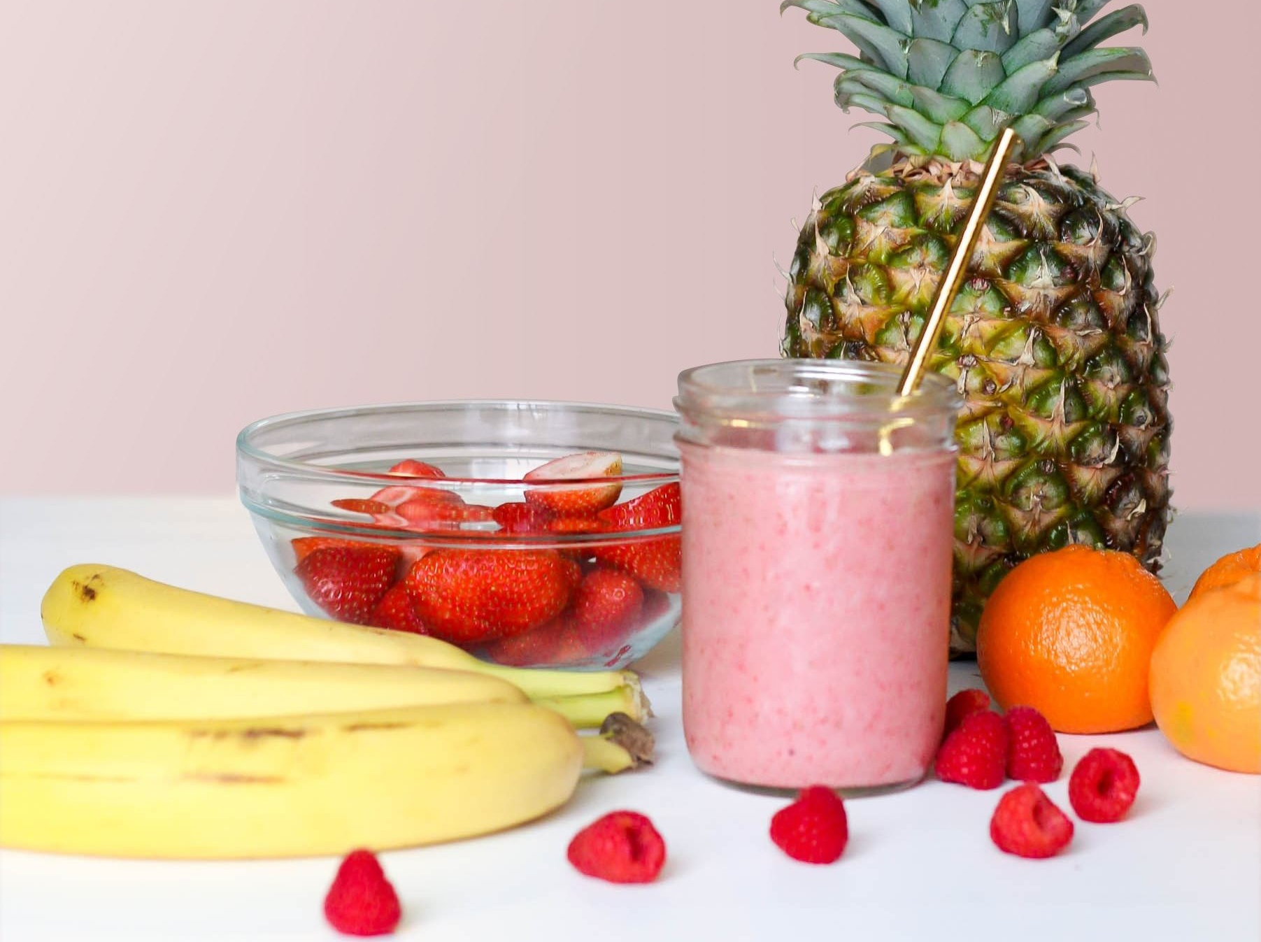 Photo of strawberries, bananas, oranges, pineapple, and a smoothie.